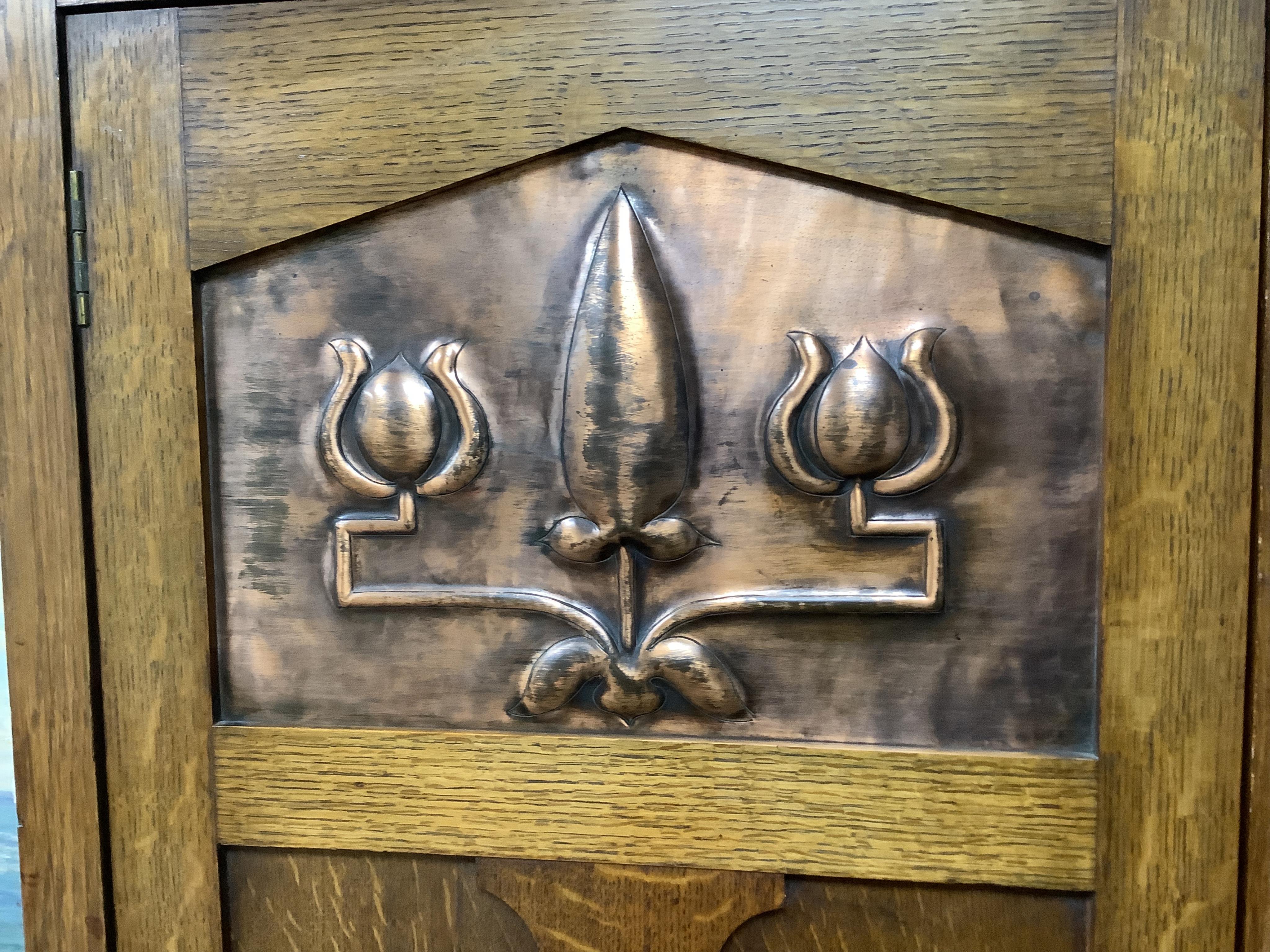 Manner of Liberty & Co: An Arts and Crafts embossed copper mounted oak hall cupboard